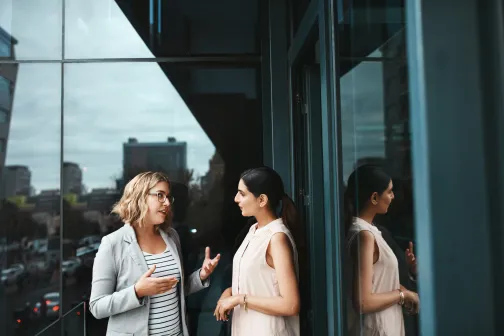two female business women talking infront of the office